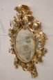Importante specchio ovale antico a cartoccio in legno intagliato e dorato, XVIII secolo                            