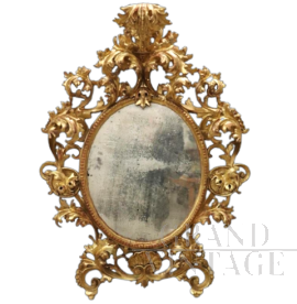 Importante specchio ovale antico a cartoccio in legno intagliato e dorato, XVIII secolo