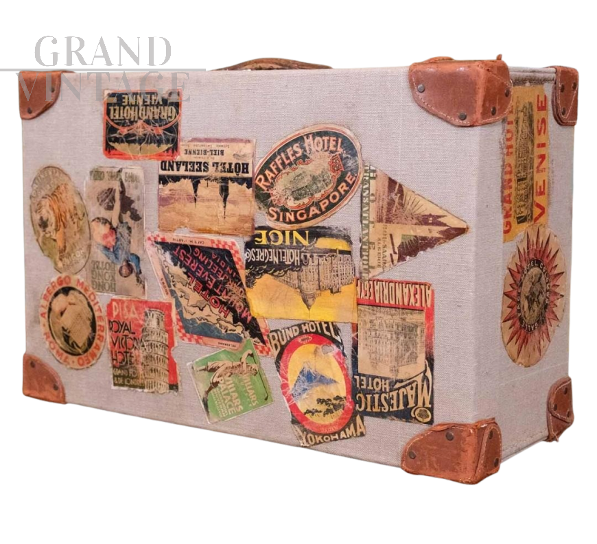 Valigia vintage in tessuto beige e cuoio marrone con adesivi di viaggio                            