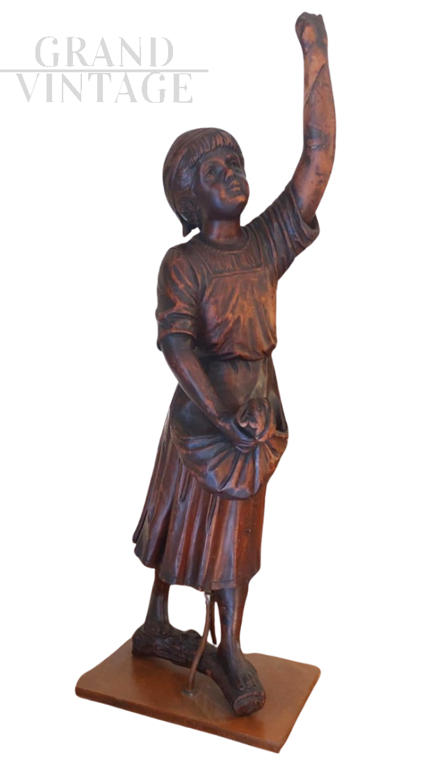 Wooden sculpture with a girl picking olives